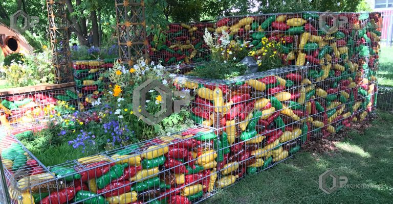 Габионные конструкции окруженные растениями и наполненные 7000 разноцветными пластиковыми бутылками